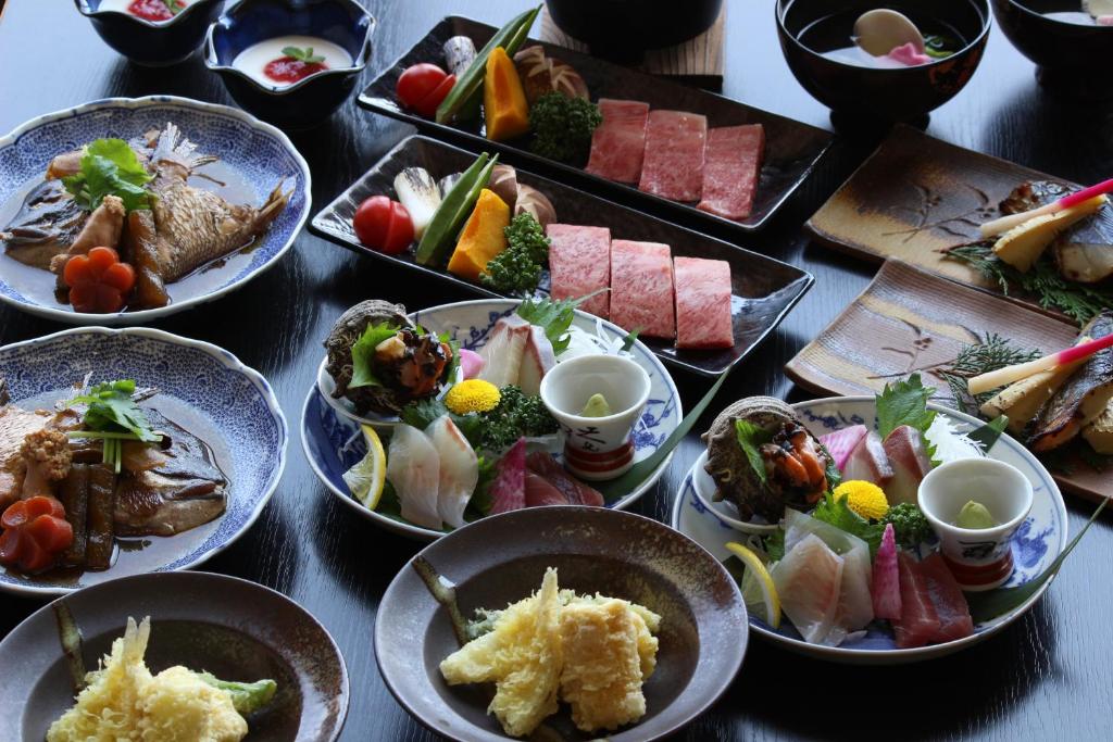 une table pleine d'assiettes de nourriture sur une table dans l'établissement 坂本屋旅館, à Kyōtango
