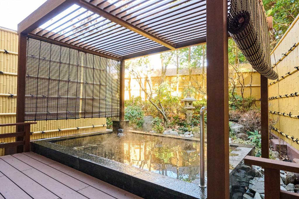 un patio avec un étang et une pergola dans l'établissement Laforet Hakone Gora Yunosumika, à Hakone