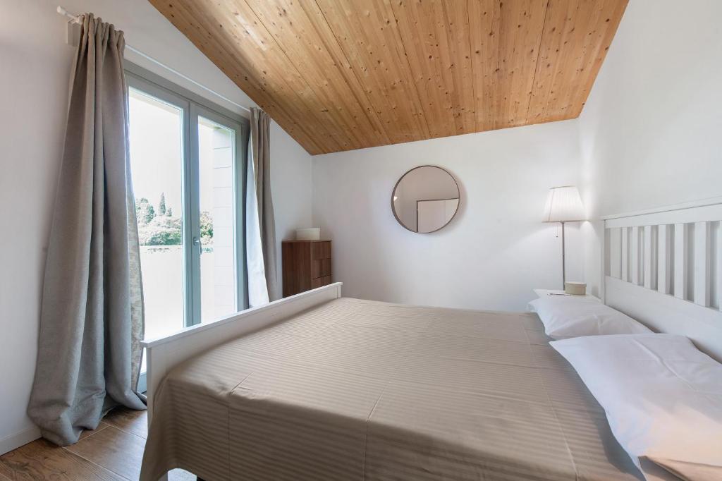 une chambre avec un lit et une grande fenêtre dans l'établissement Le Golfette Ville al Golf 1, à Manerba del Garda 26 autres photos