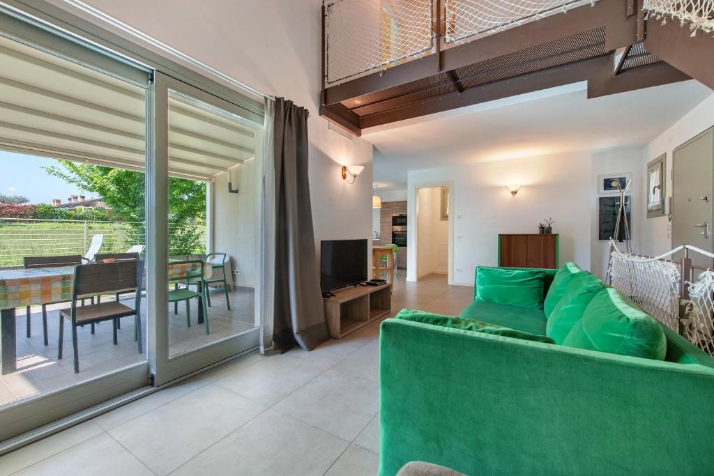 un salon avec un canapé vert et une table dans l'établissement Le Golfette Ville al Golf 1, à Manerba del Garda