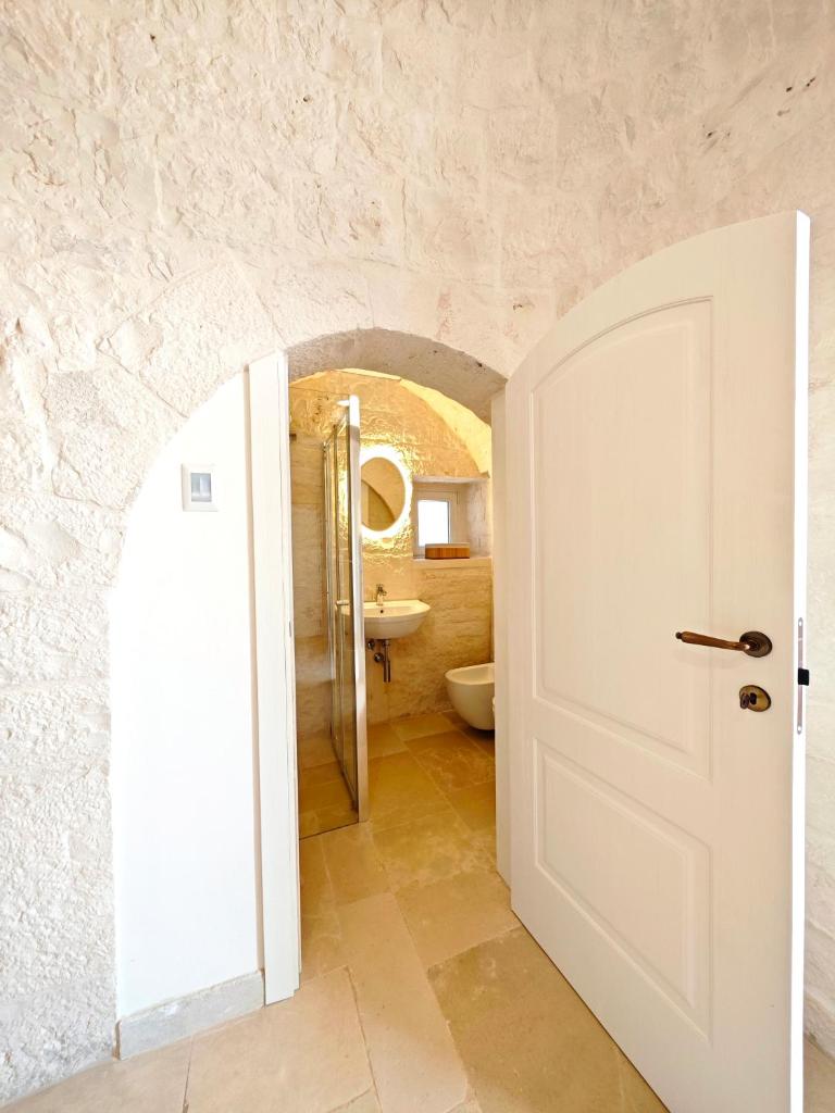 La salle de bains est pourvue d'une porte blanche et de toilettes. dans l'établissement Trullo dueConi, à Alberobello