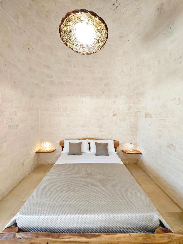 une chambre avec un grand lit et un lustre dans l'établissement Trullo dueConi, à Alberobello