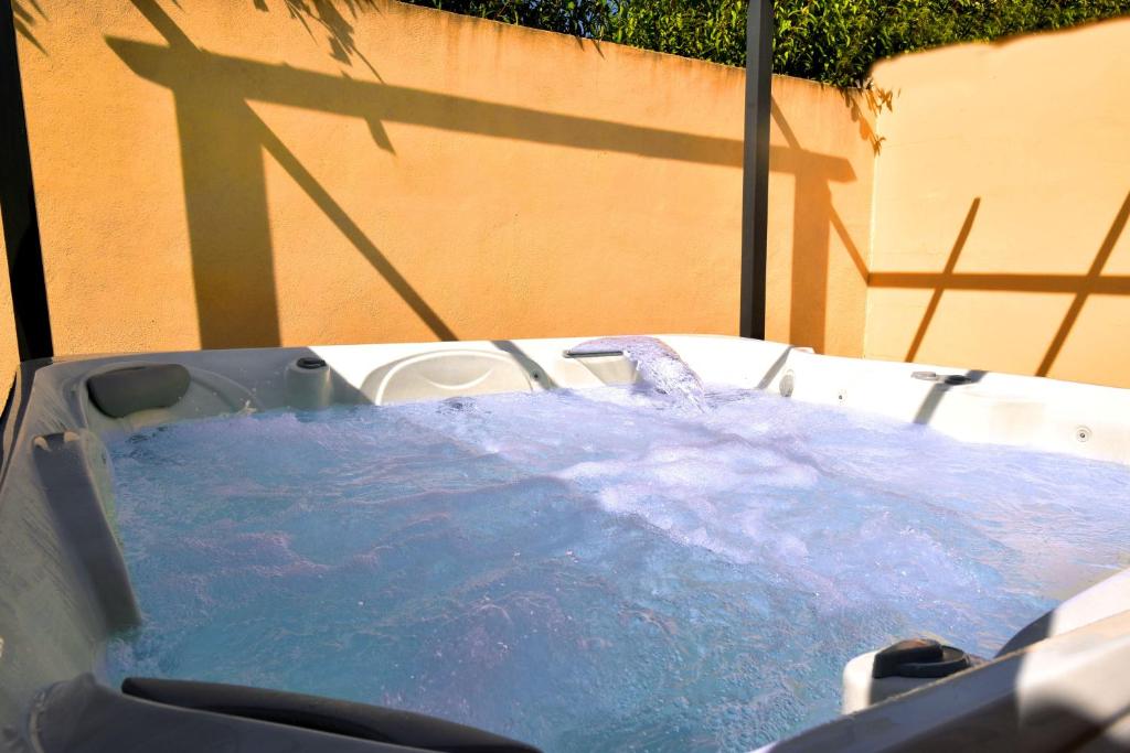 un bain à remous rempli d'eau bleue à côté d'un mur dans l'établissement Villa Spacieuse au Calme Absolu avec Grande Piscine Jacuzzi Chauffé - Grand Jardin Sans Vis a vis- Salle de Jeux avec Fresque du Nougat - Ideal Familles et Groupes Drome Provencale, à Montélimar