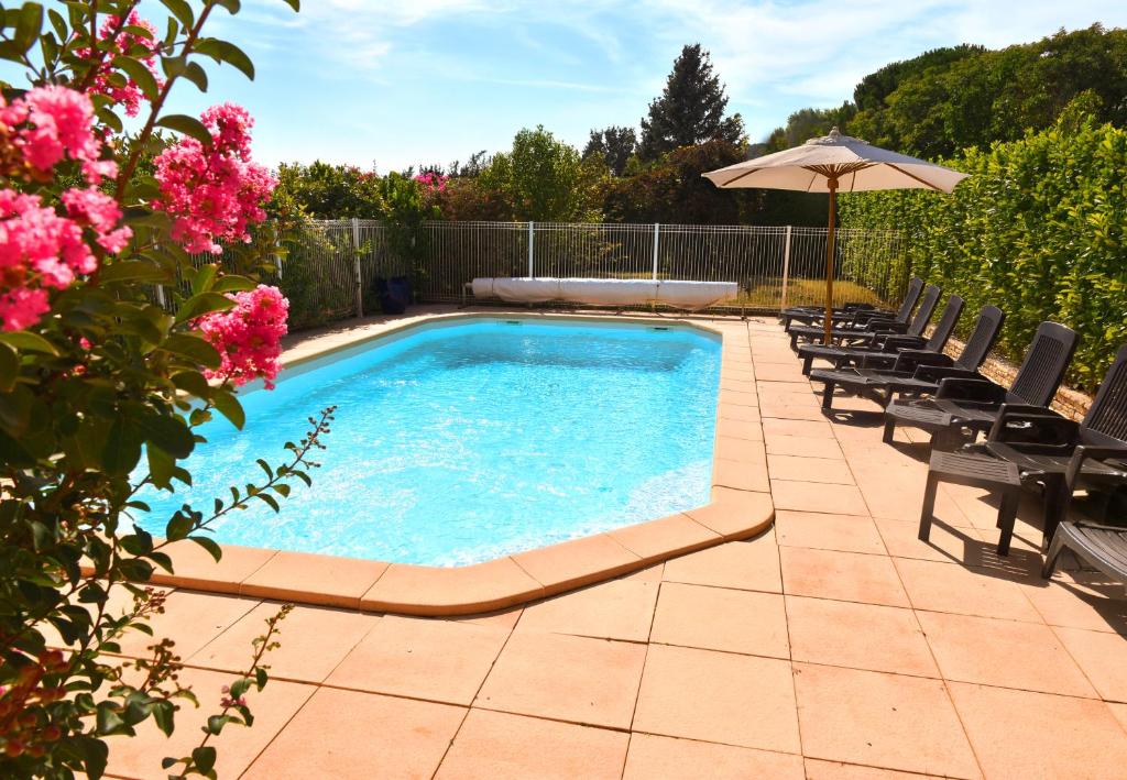 - une piscine avec des chaises, un parasol et des fleurs roses dans l'établissement Villa Spacieuse au Calme Absolu avec Grande Piscine Jacuzzi Chauffé - Grand Jardin Sans Vis a vis- Salle de Jeux avec Fresque du Nougat - Ideal Familles et Groupes Drome Provencale, à Montélimar