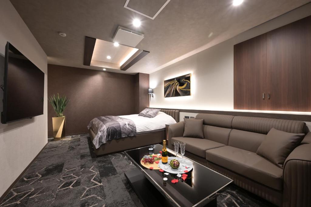 un salon avec un canapé et un lit dans l'établissement Hotel Victoria Court Aasahikawa-Adult Only, à Asahikawa