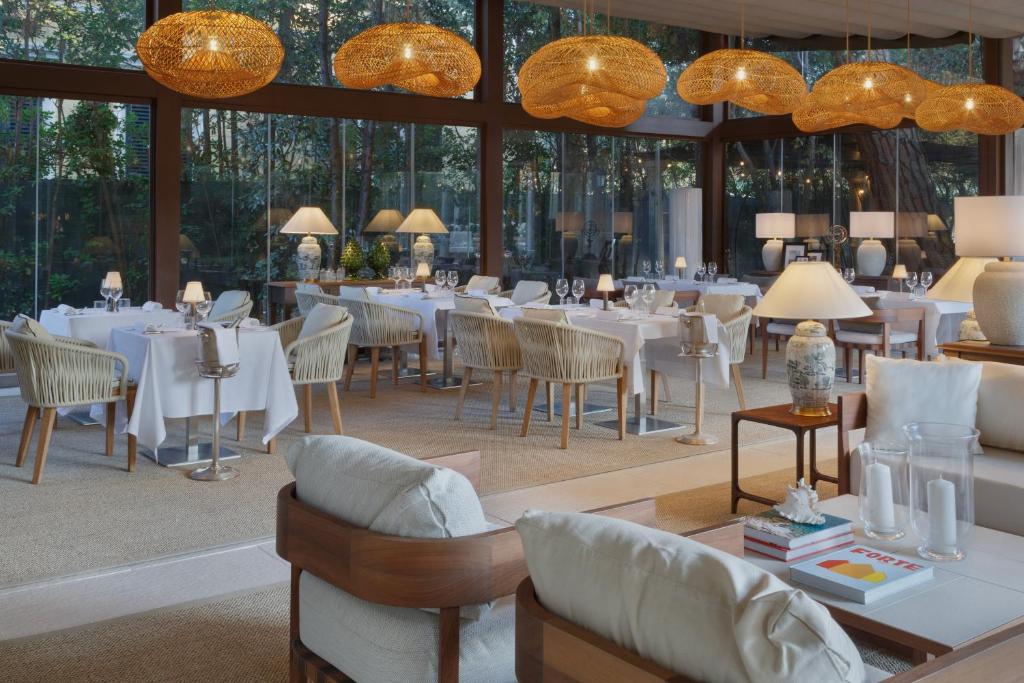 un restaurant avec des tables et des chaises blanches et des fenêtres dans l'établissement Grand Hotel Imperiale, à Forte dei Marmi