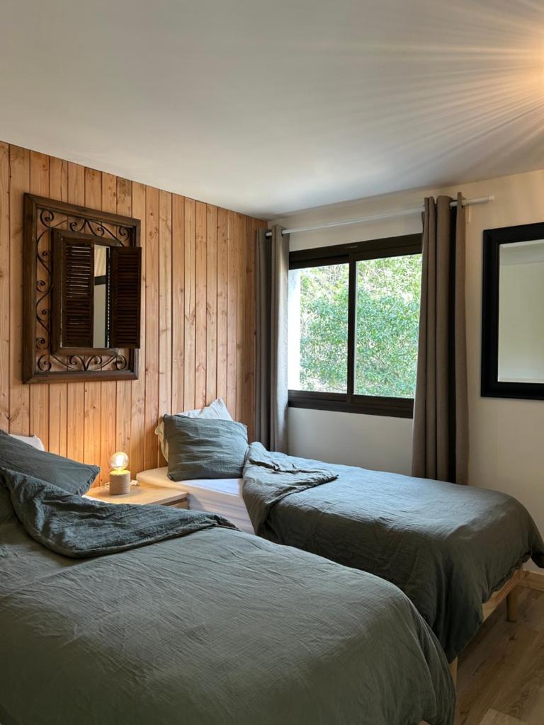 une chambre avec deux lits, un miroir et une fenêtre dans l'établissement Les Chalets de Labeaume, à Labeaume