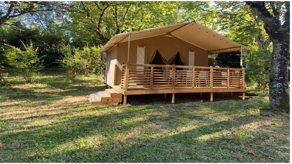 une tente marron dans un champ avec un arbre dans l'établissement camping le Faillal, à Montpezat-de-Quercy