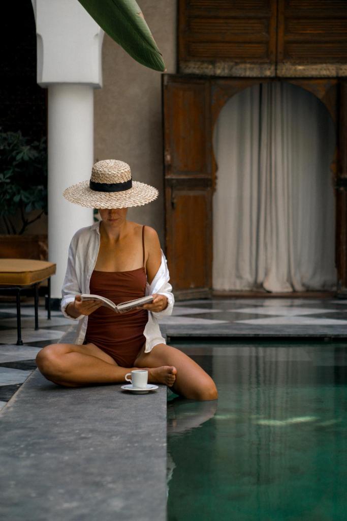 une femme assise sur le sol en train de lire un livre dans l'établissement Sakkan, à Marrakech