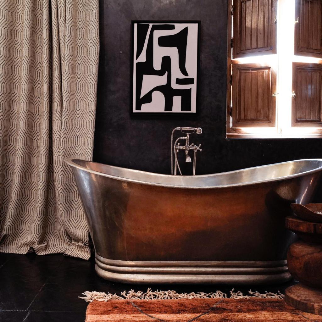 La salle de bains est pourvue d'une baignoire en cuivre et d'une fenêtre. dans l'établissement Sakkan, à Marrakech
