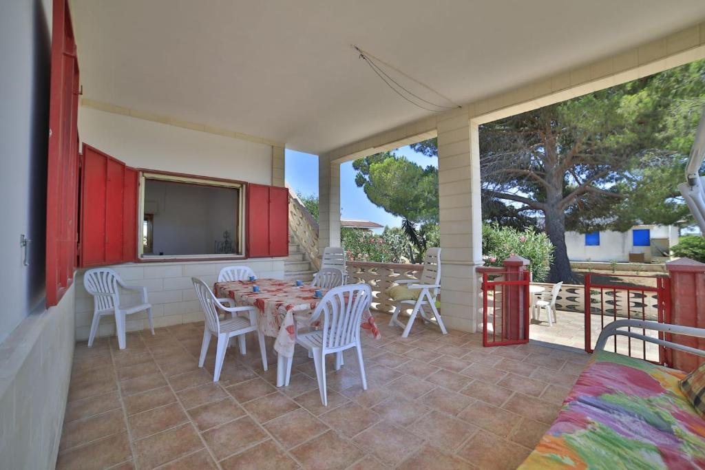 une terrasse avec une table, des chaises et une télévision dans l'établissement Villetta Giusy con piscina a soli 700 mt dalla spiaggia di San Pietro in Bevagna, à San Pietro in Bevagna
