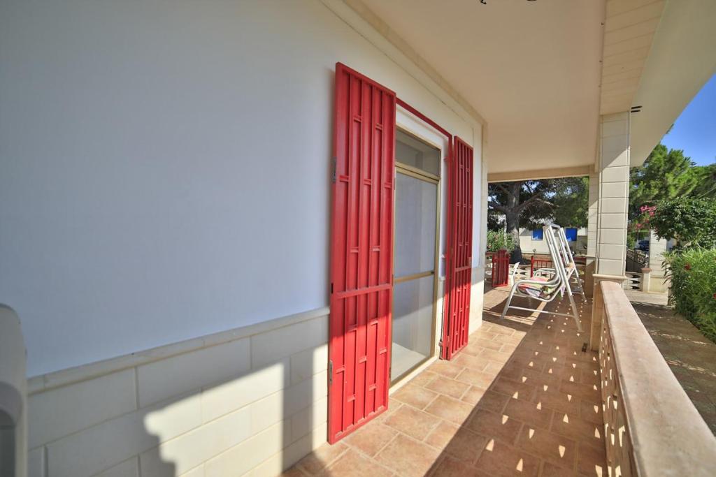 une paire de portes rouges sur le côté du bâtiment dans l'établissement Villetta Giusy con piscina a soli 700 mt dalla spiaggia di San Pietro in Bevagna, à San Pietro in Bevagna 33 autres photos