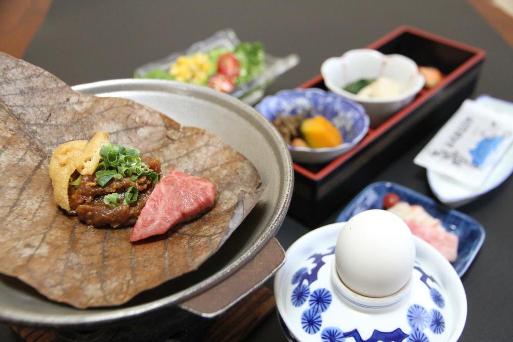 une table avec une assiette de nourriture et des bols de nourriture dans l'établissement ひらゆの森別邸湯う香三蔵庵, à Takayama