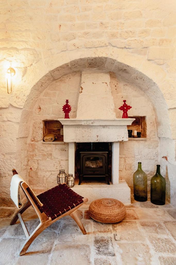 - un salon avec une cheminée en pierre et une chaise dans l'établissement Trullo Zaira, à Alberobello