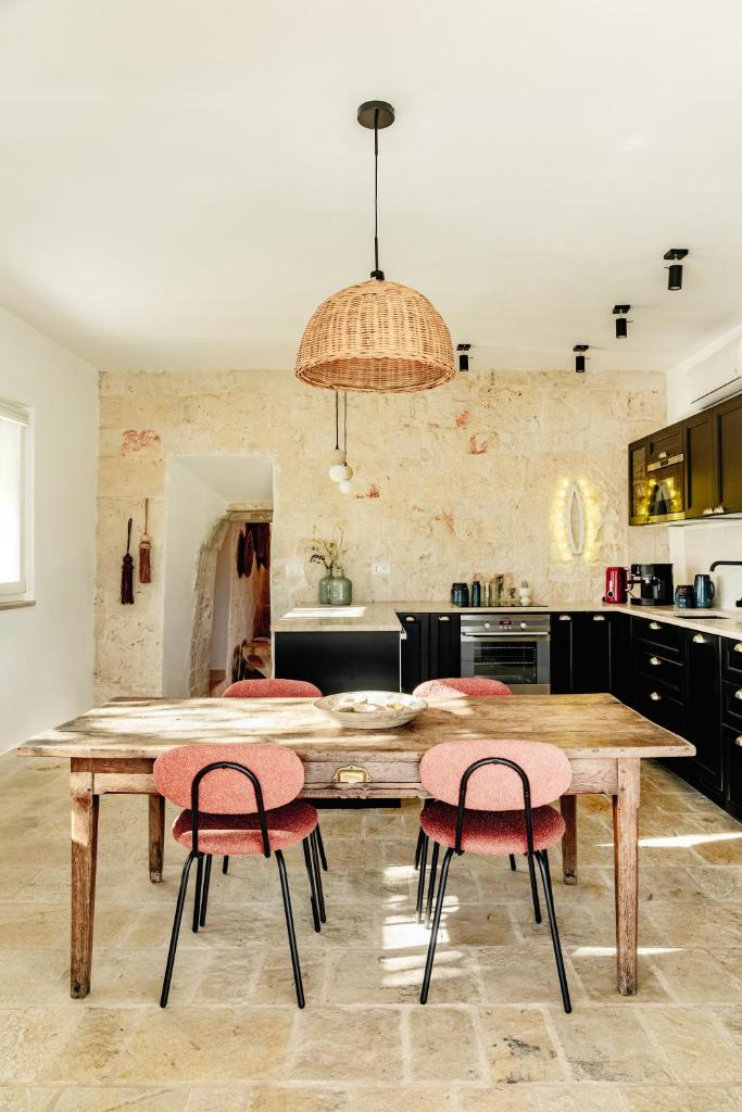 une cuisine avec une table en bois et deux chaises roses dans l'établissement Trullo Zaira, à Alberobello