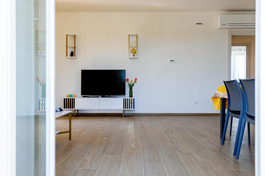 un salon avec une télévision et une table avec des chaises dans l'établissement Villa Ophite, à Offida
