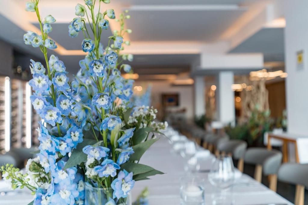 - une grande table avec des fleurs bleues et blanches dans l'établissement Grand Hotel Faraglioni, à Aci Trezza