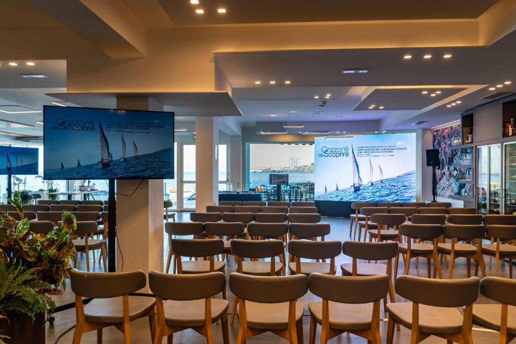 une grande pièce avec des rangées de chaises et un écran dans l'établissement Grand Hotel Faraglioni, à Aci Trezza