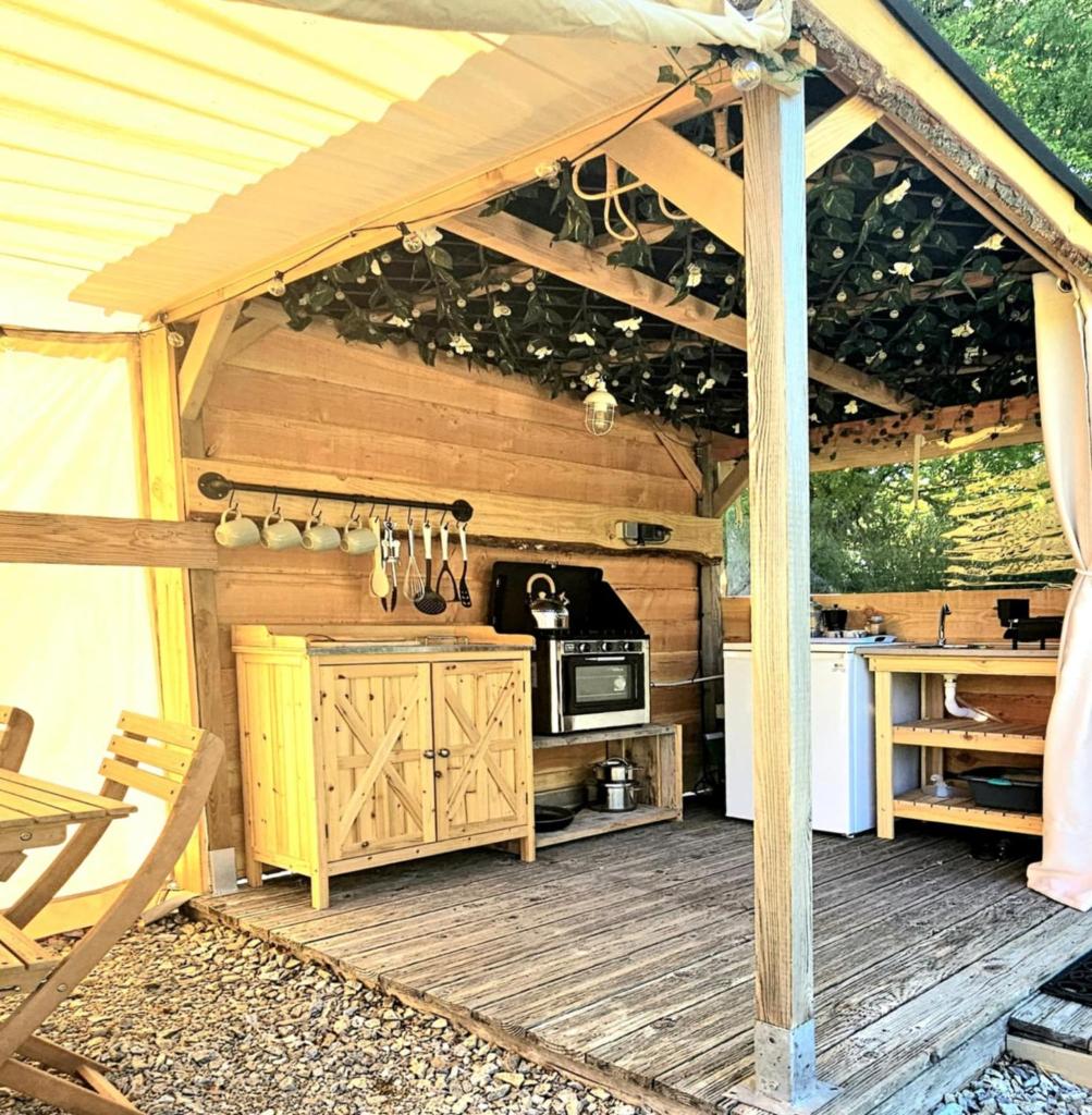 une cuisine extérieure avec auvent sur une terrasse en bois dans l'établissement Lotus Belle Tipi at Le Ranch Camping et Glamping, à Madranges