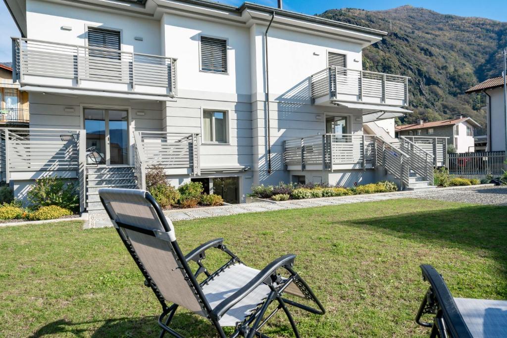 une chaise assise dans l'herbe devant une maison dans l'établissement Villa Sunset - Luxury property with pool & large private garden and parking, few steps from the beach, ideal for singles, couples and a family, à Dervio