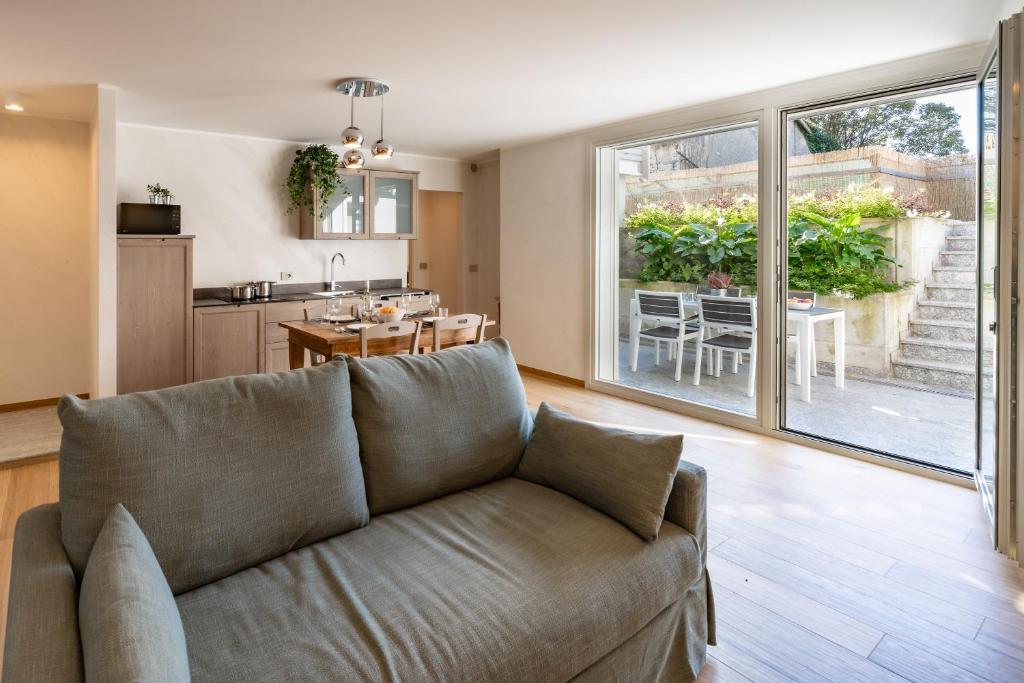 un salon avec un canapé et une cuisine dans l'établissement Villa Sunset - Luxury property with pool & large private garden and parking, few steps from the beach, ideal for singles, couples and a family, à Dervio