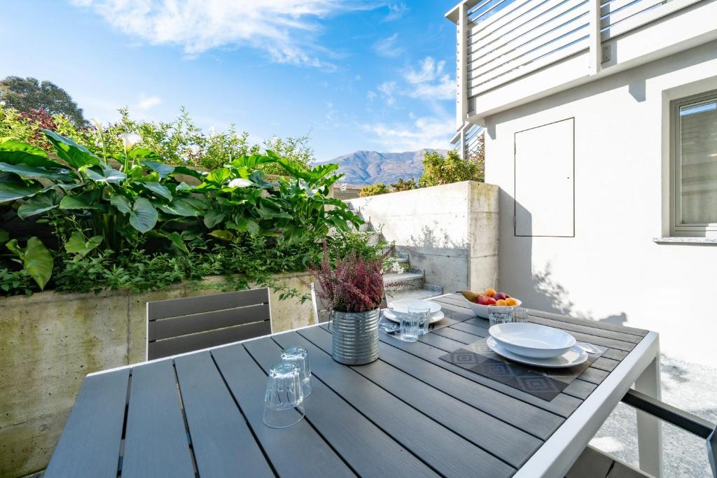 - une table en bois avec des assiettes sur la terrasse dans l'établissement Villa Sunset - Luxury property with pool & large private garden and parking, few steps from the beach, ideal for singles, couples and a family, à Dervio 30 autres photos