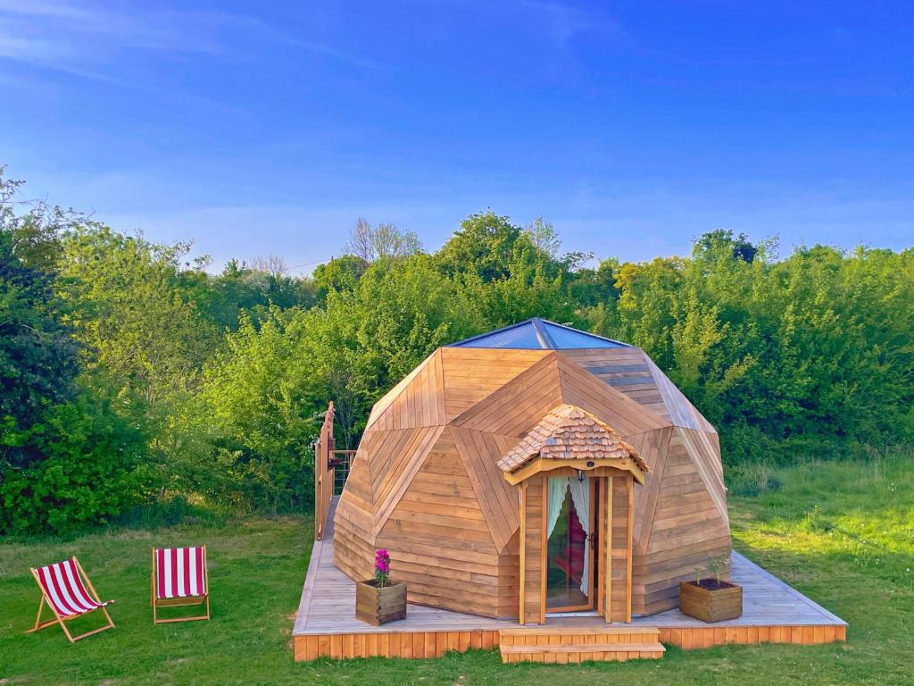 une cabane en bois d'iguane dans un champ avec deux chaises dans l'établissement L'étoile de Baynes, à Cerisy-la-Forêt