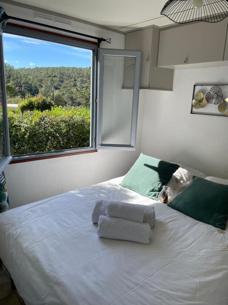 une chambre avec un grand lit blanc avec une fenêtre dans l'établissement mobile home dans un coin de paradis, à Fréjus