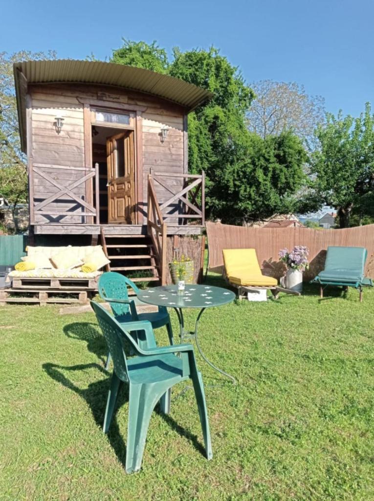 - une table et des chaises dans une cour avec cabine dans l'établissement Roulotte de la Ferme Les Chenevières, à Villers-devant-Mouzon