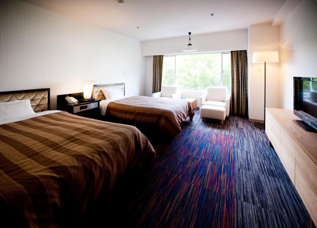 une chambre d'hôtel avec deux lits et une télévision à écran plat dans l'établissement Chaharu, à Matsuyama