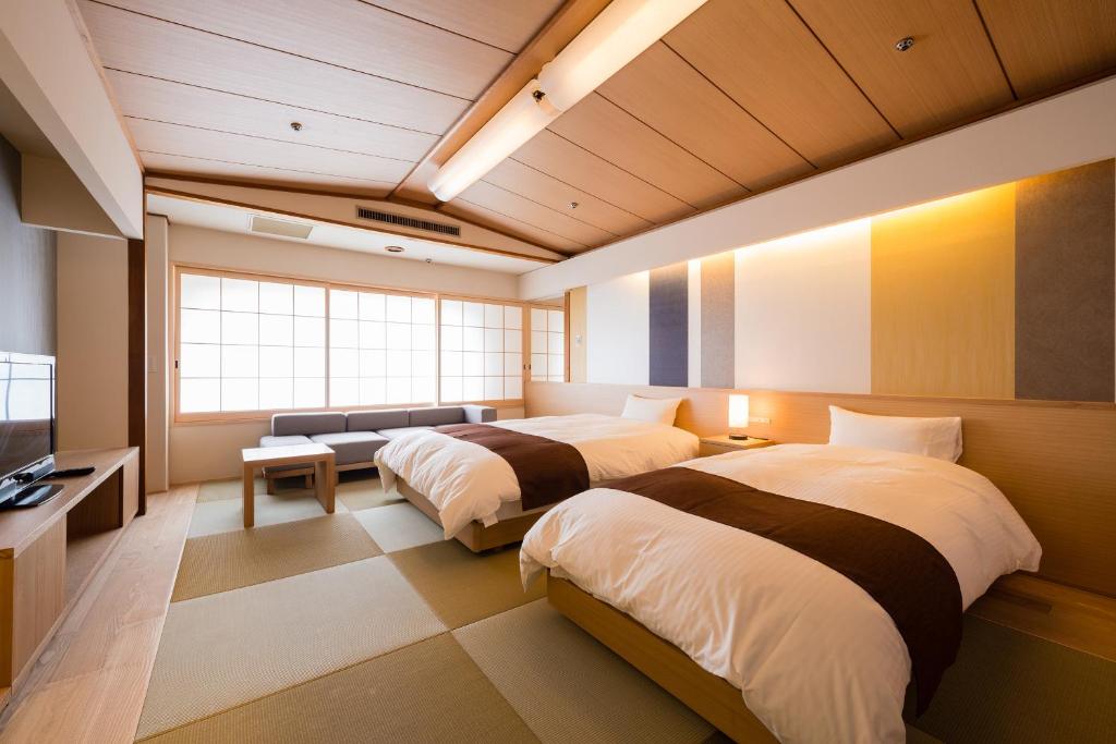 Cette chambre comprend 2 lits et une télévision. dans l'établissement Chaharu, à Matsuyama
