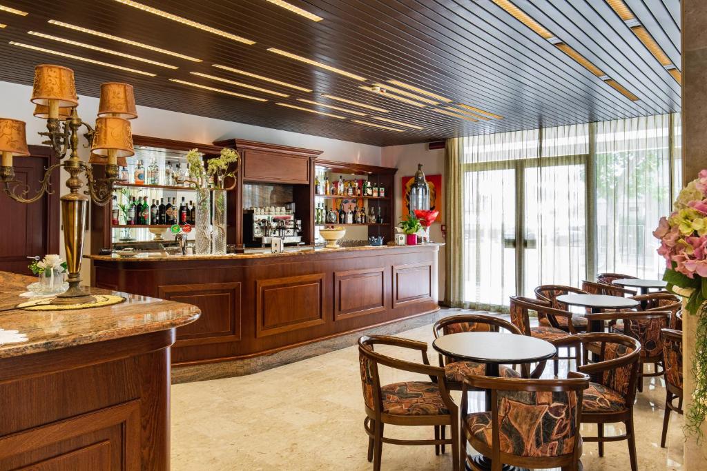 un restaurant avec un bar avec tables et chaises dans l'établissement Hotel Ambasciatori, à Cesenatico