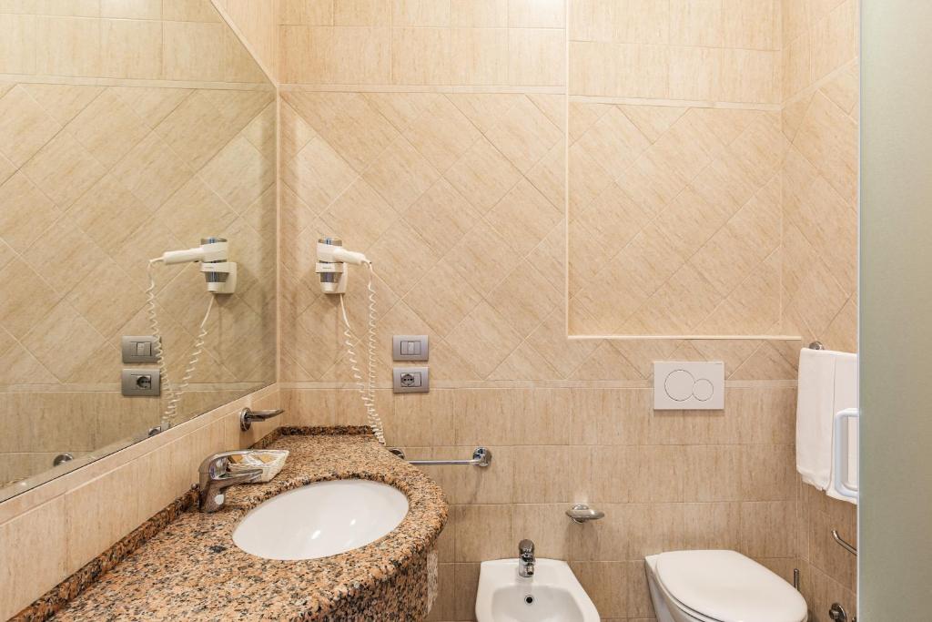 une salle de bain avec un lavabo et des toilettes dans l'établissement Hotel Ambasciatori, à Cesenatico
