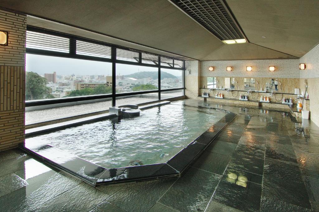 une grande piscine dans un immeuble avec une grande fenêtre dans l'établissement Chaharu, à Matsuyama