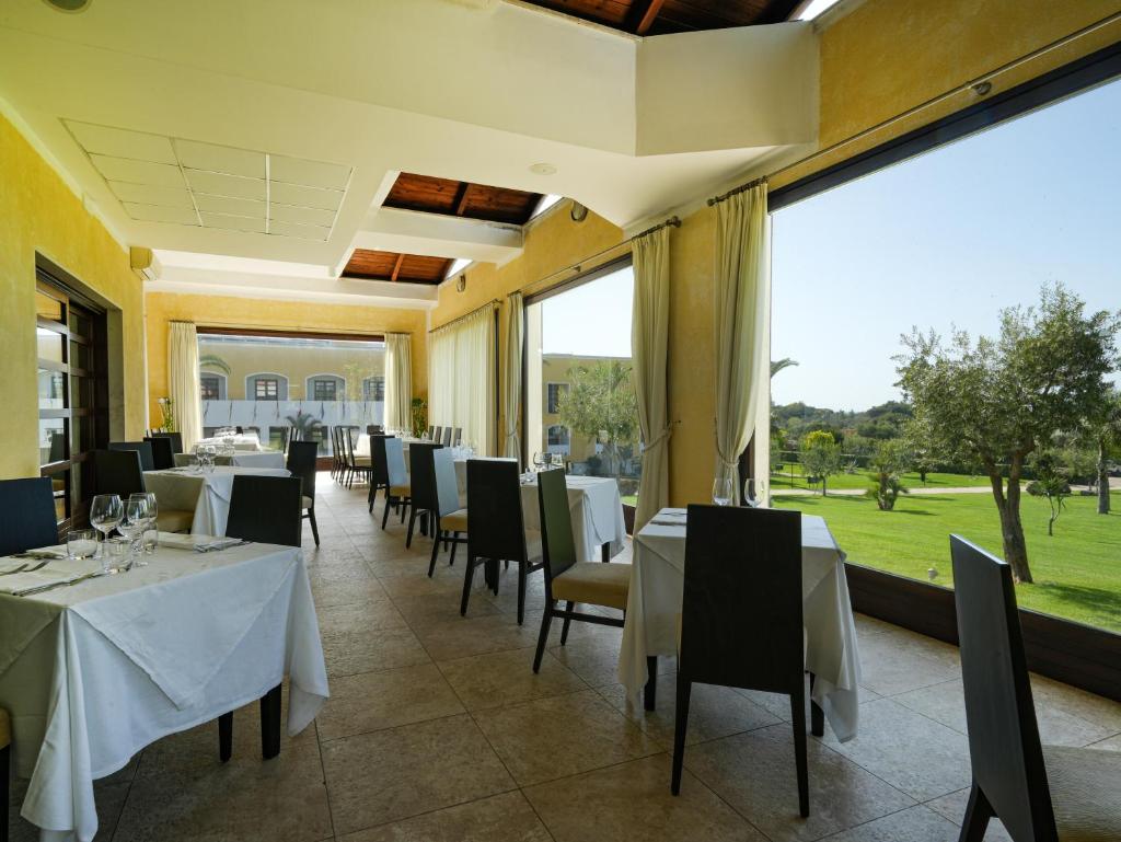 un restaurant avec des tables et des chaises blanches et de grandes fenêtres dans l'établissement GH Gallipoli Resort, à Gallipoli