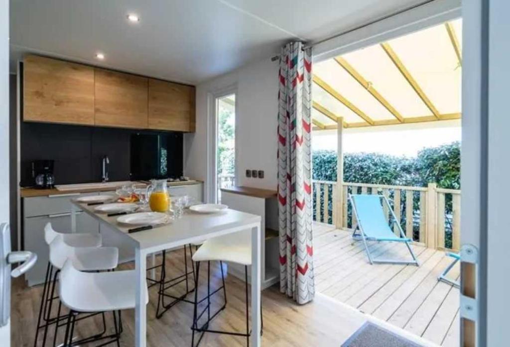 une cuisine avec une terrasse dotée d'une table et de chaises dans l'établissement Camping 4 étoiles - Piscine - efceih, à LʼÎle-dʼOlonne