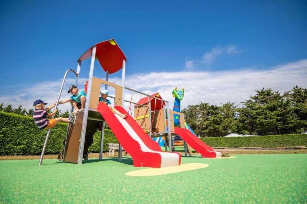 un groupe d'enfants jouant sur un toboggan dans une aire de jeux dans l'établissement Camping 3 étoiles - Piscine - ccaaffc, à Prigny