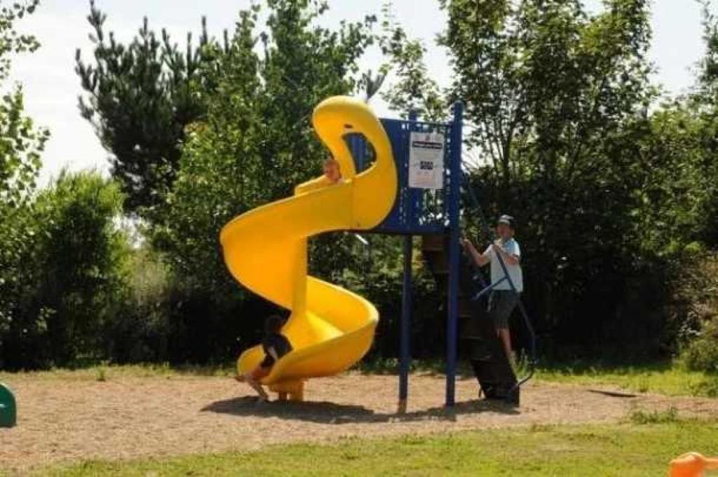 Un homme debout à côté d'un toboggan jaune dans un parc dans l'établissement Camping 3 étoiles - efdbeb, à Plobannalec-Lesconil