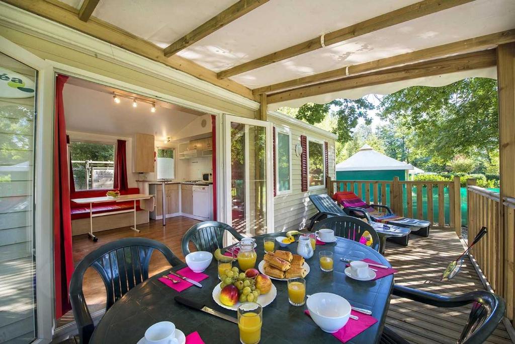 - une table avec de la nourriture et des boissons sur une terrasse couverte dans l'établissement Camping 2 étoiles - Piscine - ccab0if, à Saint-Sozy
