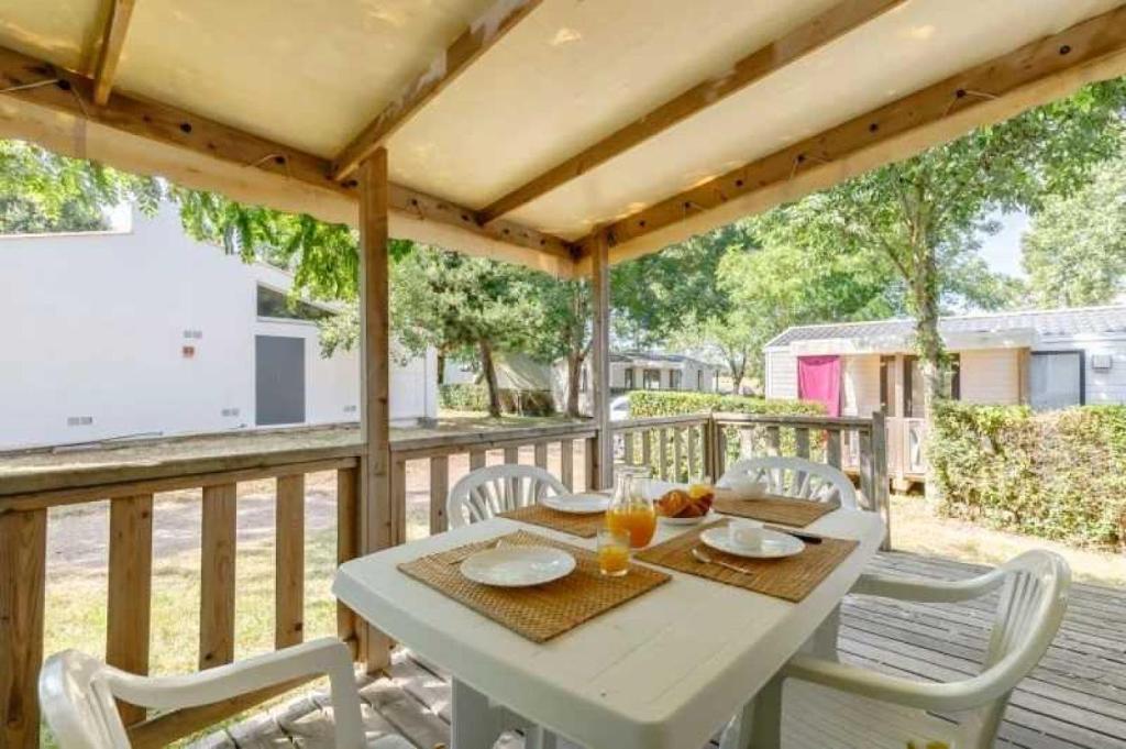 une table et des chaises blanches sur une terrasse en bois dans l'établissement Camping 3 étoiles - Piscine - ccafbhe, à Saint-Hilaire-de-Talmont