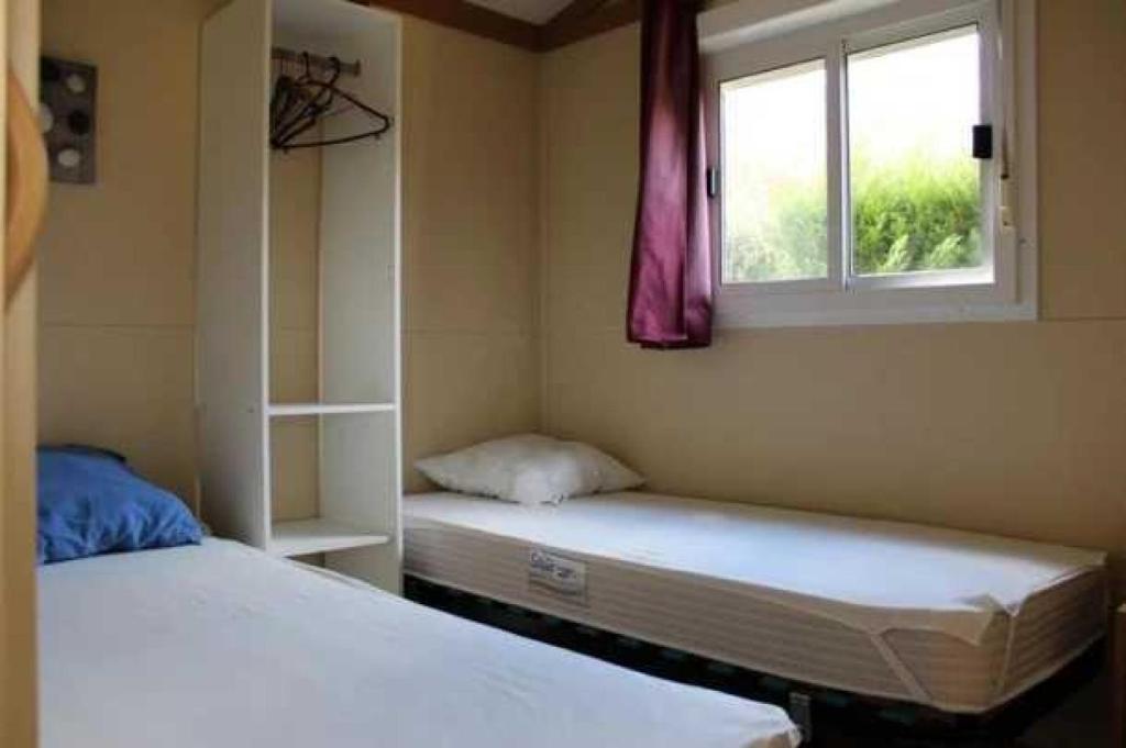 deux lits dans une chambre avec une fenêtre dans l'établissement Camping 3 étoiles - Piscine - eehgef, à Castelnau-Picampeau