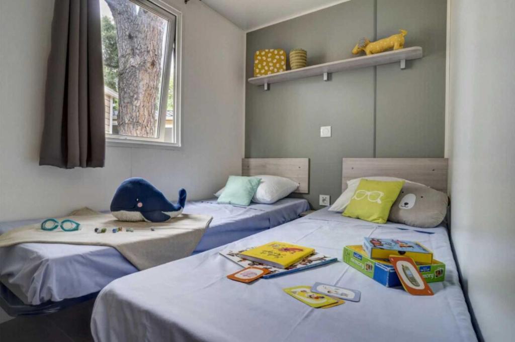 deux lits dans une chambre avec des jouets sur les lits dans l'établissement Camping - Piscine - ccai0bg, à Argelès-sur-Mer 37 autres photos