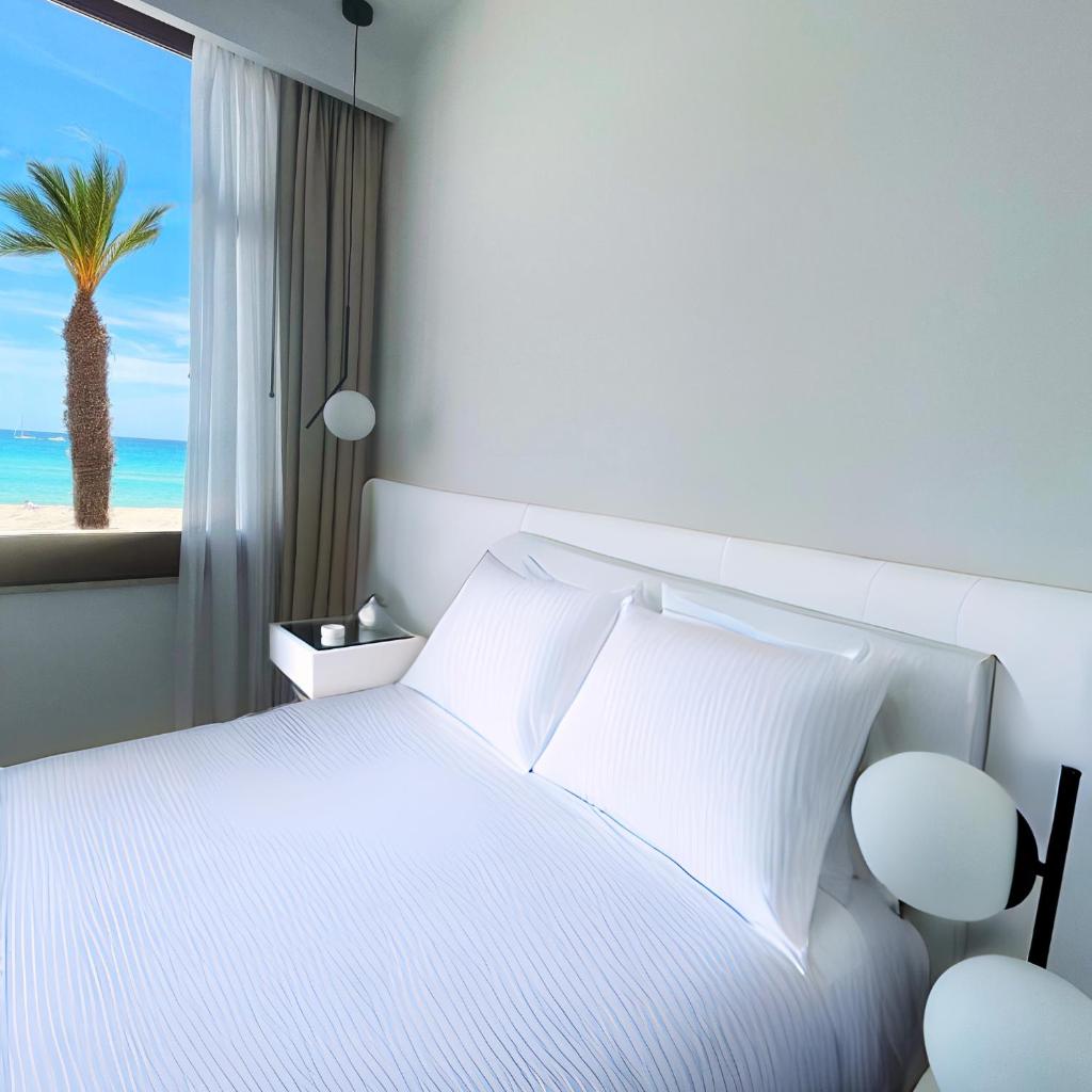- une chambre avec un lit blanc et un palmier dans l'établissement Hotel Egitarso Sul Mare, à San Vito Lo Capo