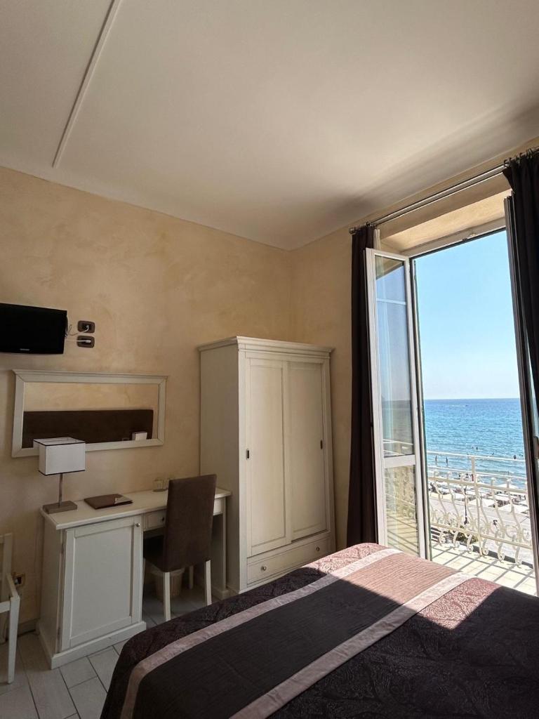 une chambre avec un lit et un bureau avec vue sur l'océan dans l'établissement Hotel Villa Igea, à Alassio 83 autres photos
