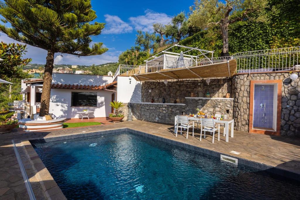 une maison avec une piscine, une table et des chaises dans l'établissement Villa La Scala, à Massa Lubrense