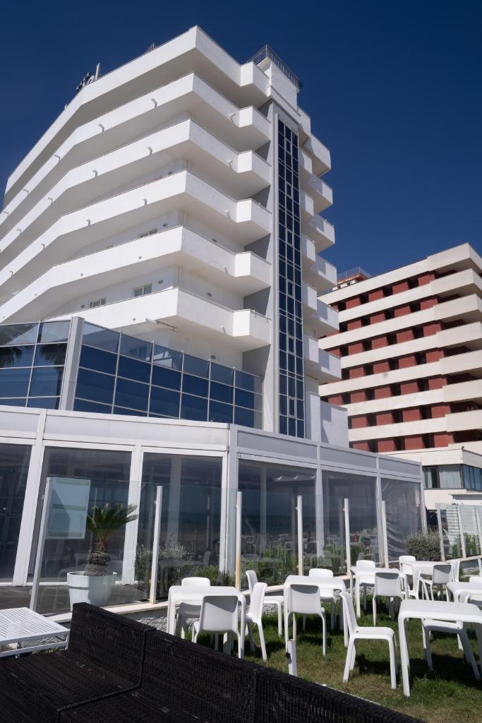 un groupe de tables et de chaises blanches devant un bâtiment dans l'établissement Sea Lion Hotel, à Montesilvano