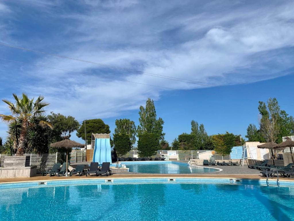 une grande piscine bleue avec chaises et parasols dans l'établissement Mobil home pour 6, près de la mer, dans un camping 4 étoiles à 20min de Montpellier., à Vic-la-Gardiole