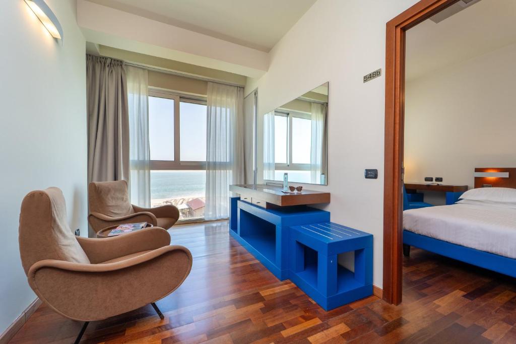 une chambre avec un lit et deux chaises et un miroir dans l'établissement Hotel Balance, à Milano Marittima 80 autres photos