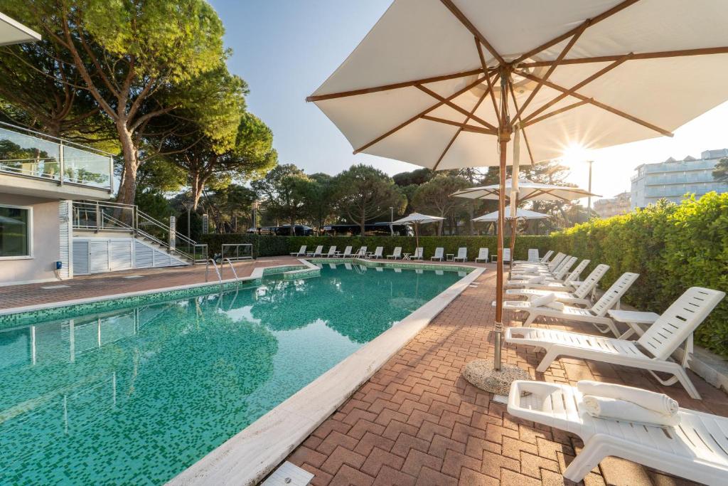 - une piscine avec des chaises blanches et un parasol dans l'établissement Hotel Balance, à Milano Marittima