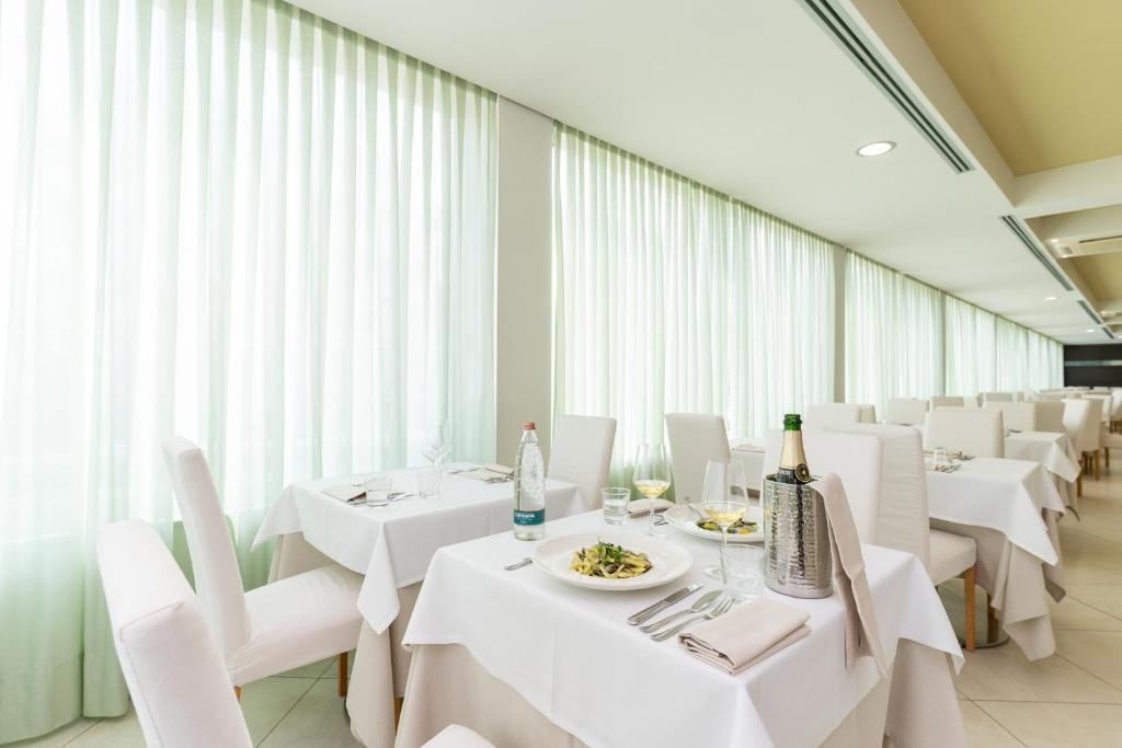 une salle à manger avec des tables blanches et des chaises blanches dans l'établissement Hotel Balance, à Milano Marittima